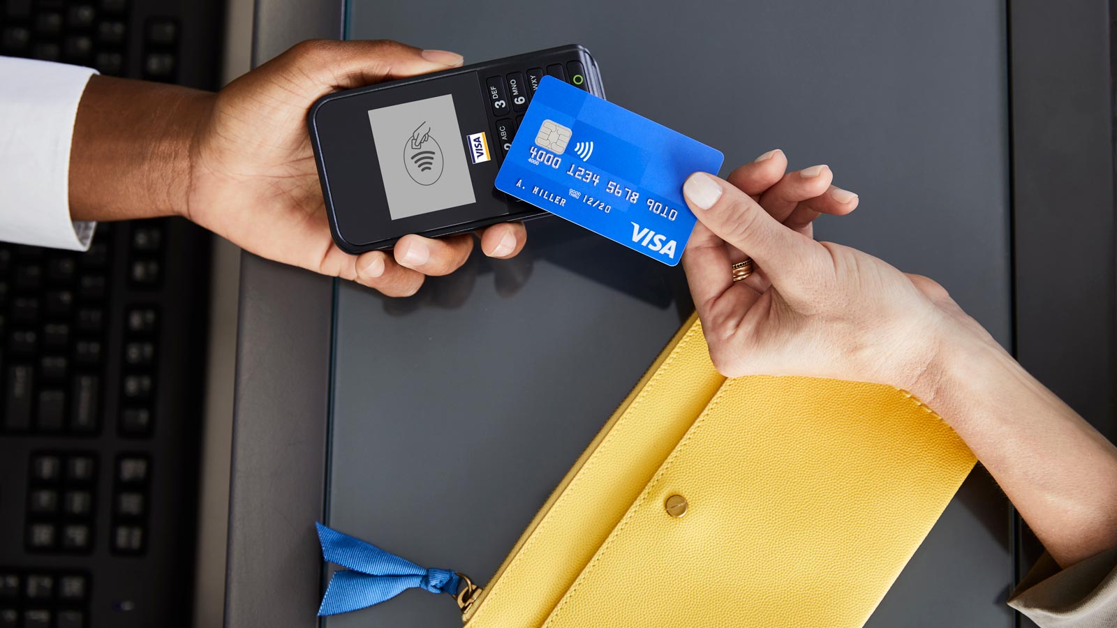Gambar dua tangan yang sedang melakukan transaksi bayar di tempat dengan kartu Visa